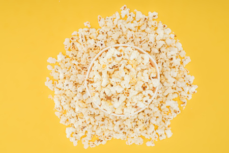 top view of carton bucket and scattered popcorn isolated on yellowの写真素材