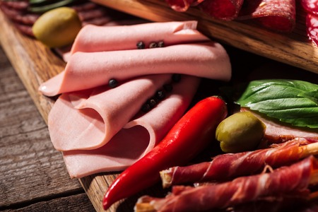 close up view of wooden cutting board with delicious sliced ham and prosciuttoの写真素材