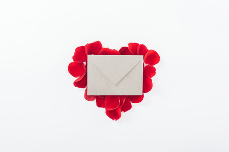 top view of envelope and heart made of red rose petals isolated on white, st valentines day conceptの写真素材