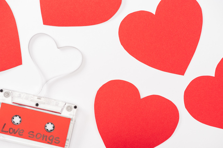 top view of audio cassette with 'love songs' lettering and heart shaped cards isolated on white, st valentines day conceptの写真素材