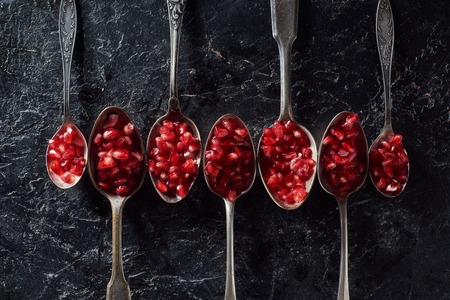 Flat lay with garnet seeds in silver spoons