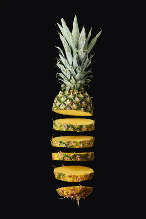sliced, tasty and sweet pineapple isolated on blackの写真素材