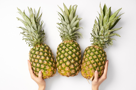 cropped view of woman holding delicious pineapples in hands on white backgroundの写真素材