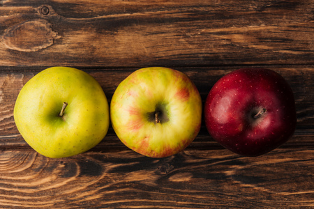 top view of row of ripe multicolored apples on wooden tableの写真素材