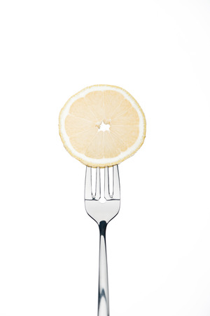 sircle slice of fresh ripe juicy lemon on fork isolated on whiteの写真素材