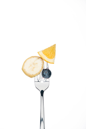 whole blueberry, slices of orange and banana on fork isolated on whiteの写真素材