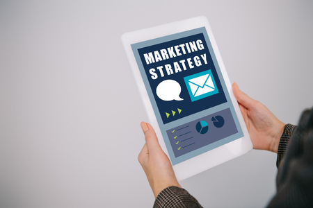 cropped view on businesswoman using digital tablet with marketing strategy isolated on greyの写真素材