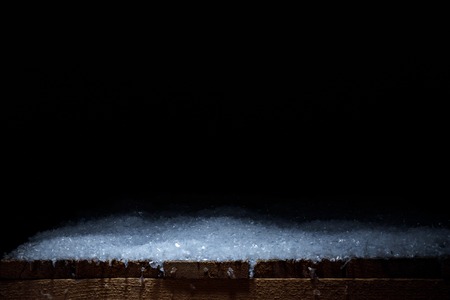striped wooden rustic material covered with snow on blackの写真素材