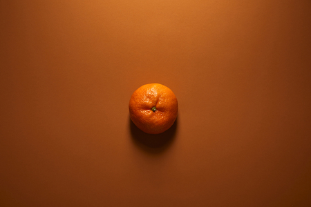 top view of whole single ripe tangerine on brown backgroundの写真素材