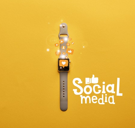 top view of smartwatch with icons and social media lettering on yellow surfaceの写真素材