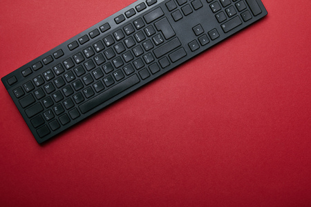 Top view of black computer keyboard on red background with copy spaceの写真素材