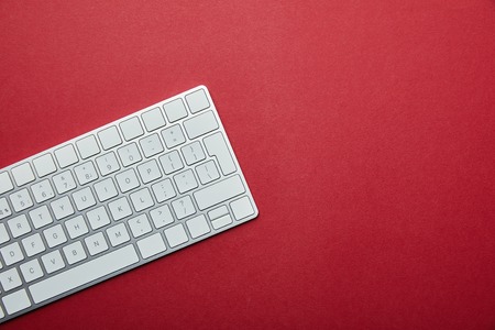 Top view of white computer keyboard on red background with copy spaceの写真素材