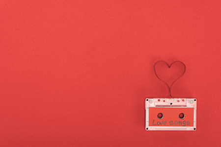 elevated view of audio cassette with lettering love songs and heart symbol made of tape isolated on red, st valentine day conceptの写真素材