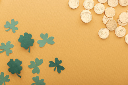 top view of golden coins with dollar signs, shamrocks and copy space isolated on orange, st patrick day conceptの写真素材