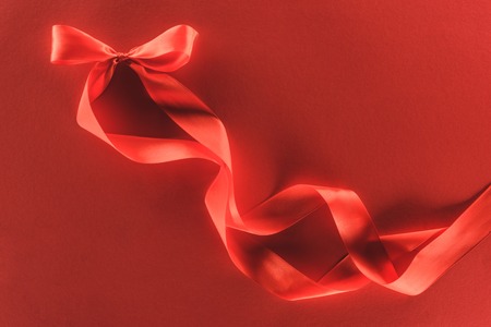 top view of red festive ribbon bow isolated on red, st valentine day conceptの写真素材