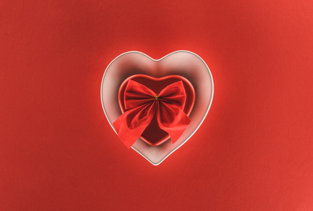 top view of heart shaped present box and festive ribbon isolated on red, st valentine day conceptの写真素材