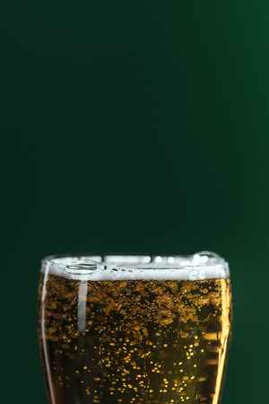 close up of beer glass with foam and bubbles isolated on green, st patrick day conceptの写真素材