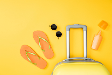 top view of baggage, sunglasses and flip flops on yellow backgroundの写真素材