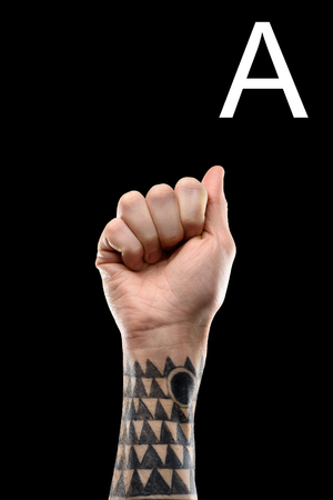 tattooed male hand showing latin letter - A, sign language, isolated on blackの写真素材