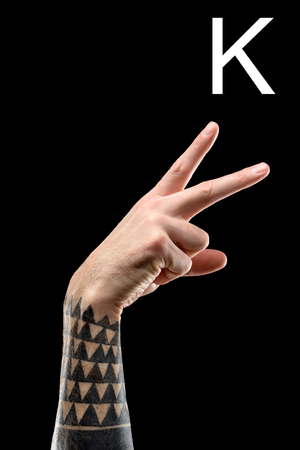 Partial view of tattooed male hand showing cyrillic letter, deaf and dumb language, isolated on blackの写真素材