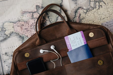 top view of leather bag with passport, ticket, smartphone and earphones on mapの写真素材