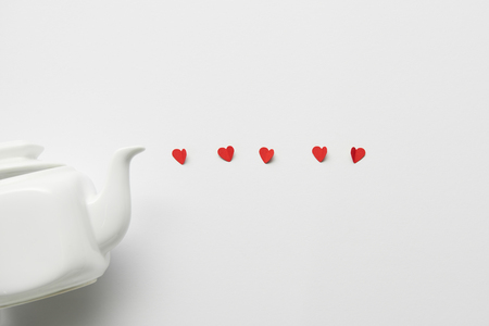 top view of tea pot and red paper cut hearts on white backgroundの写真素材