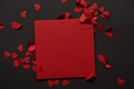 top view of red blank greeting card and paper cut hearts on black backgroundの写真素材