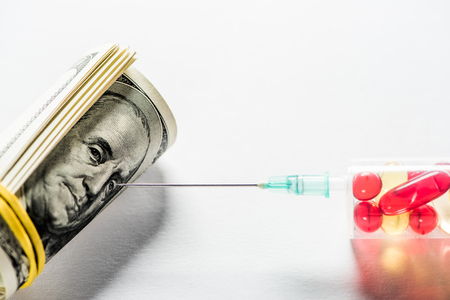 close up of syringe with pills near money roll on white backgroundの写真素材