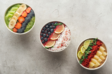 Top view of healthy organic smoothie bowls with fruits on grey backgroundの写真素材