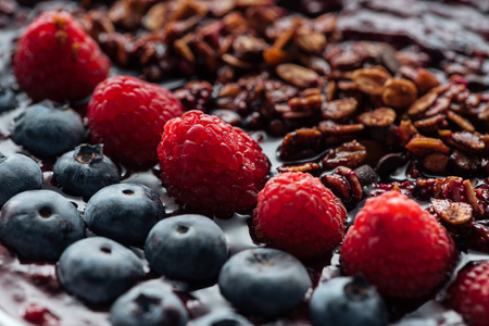 Selective focus of blueberries, raspberries and homemade granola in smoothie bowlの写真素材