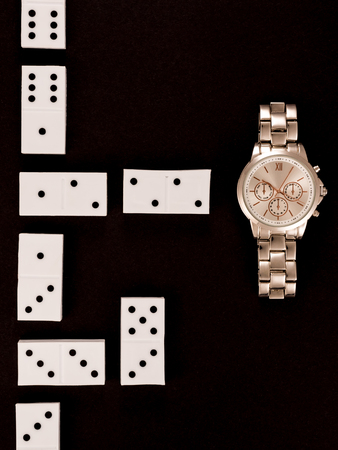 Top view of luxury wristwatch lying near dominoes isolated on blackの写真素材