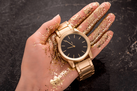 cropped view of golden wristwatch in hand of womanの写真素材