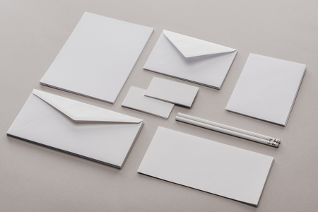Flat lay with envelopes, cards, sheets of paper and pencils on grey backgroundの写真素材