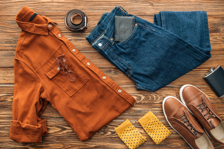 Flat lay with shirt, jeans and shoes with accessories on wooden backgroundの写真素材