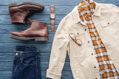 Flat lay with jeans, checkered shirt and leather boots on wooden backgroundの写真素材
