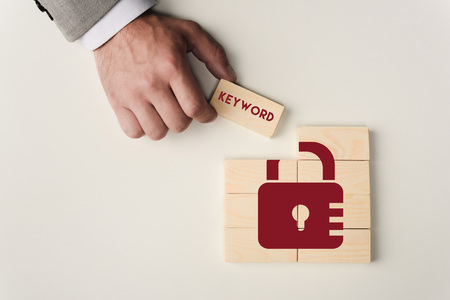partial view of man holding brick with 'keyword' lettering over wooden blocks with lock icon...