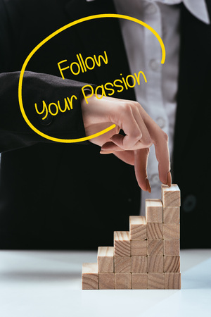 cropped view of woman climbing with fingers wooden career ladder, 'follow your passion' lettering on foregroundの写真素材