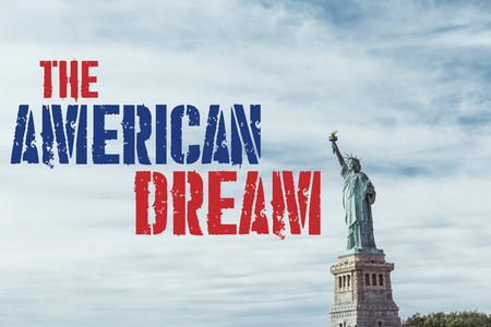 STATUE OF LIBERTY, NEW YORK, USA - OCTOBER 8, 2018: statue of liberty in new york against blue cloudy sky background with "the american dream" lettering, usaの写真素材