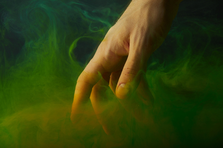 cropped view of hand in water with green paint swirlsの写真素材