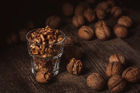 Close up view of tasty shelled walnuts in glass on wooden tableの写真素材