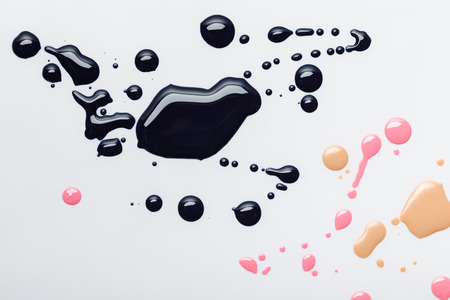 top view of abstract black spills with pink and beige drops isolated on greyの写真素材