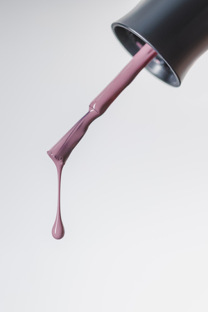 close up view of nail polish brush with lilac drop isolated on greyの写真素材