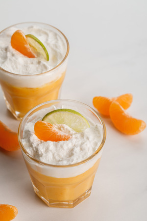 two glasses with sweet citrus desserts with tangerine and lime slicesの写真素材