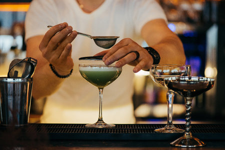 selective focus of bartender preparing alcoholic cocktail using sieveの写真素材