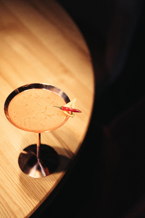 alcoholic cocktail in metal glass decorated with chili pepper and nacho chip on wooden tableの写真素材