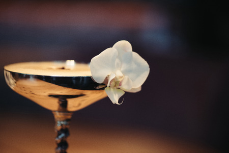 close up of alcoholic cocktail in metal glass decorated with orchid flower on dark backgroundの写真素材