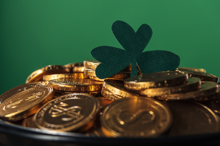 Shiny golden coins with shamrock isolated on green, st patrick day conceptの写真素材