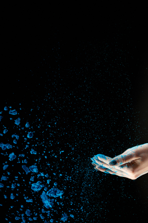Cropped view of adult woman throwing blue holi powder on black backgroundの写真素材