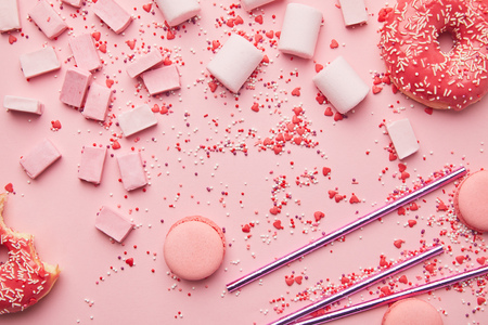top view of sweet macaroons, marshmallows and candies isolated on pinkの写真素材