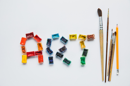 top view of paintbrushes, pencil and art lettering made of paints on white backgroundの写真素材